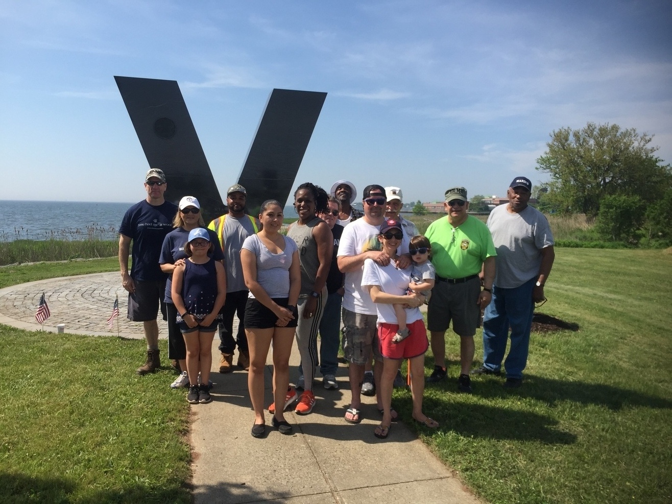 Group of people in front of a large metal V.