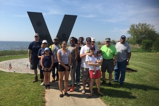 Group of people in front of a large metal V.